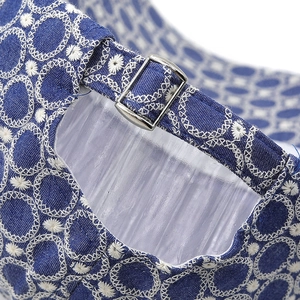Dettaglio della fibbia metallica e del ricamo bianco sul berretto da baseball in denim blu