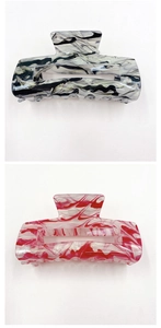 Close-up of black and pink marble texture acrylic hair claws in rectangular design
