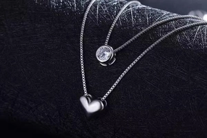 Detailed view of silver double-layered necklace with zircon heart and round charms