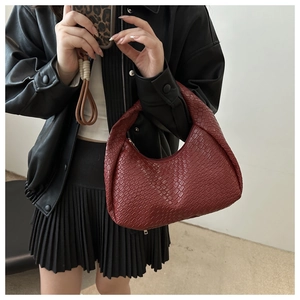 Detailed close-up of dark red woven leather texture and integrated handle on hobo bag