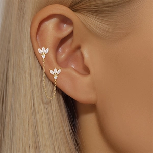 Detail of gold leaf earring chain with white zircon crystals worn by a female model