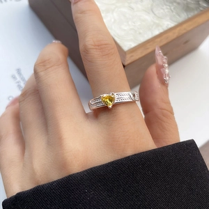 Detail of a 925 silver ring featuring a yellow heart gemstone and woven band texture