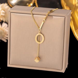 Close-up of gold titanium necklace featuring a geometric cube pendant and unique link chain