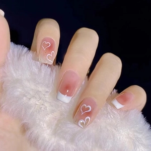 Pink blush press-on nails with white heart art and French tips on a fluffy background