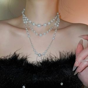 Close-up of triple-layered pearl necklace with silver chain on model neck