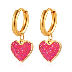 Créoles dorées avec pendentifs cœurs roses scintillants sur fond blanc épuré