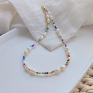 Detail of colorful bohemian beaded necklace with natural freshwater pearls on ceramic plate