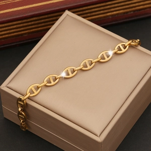 Close-up of golden coffee bean link chain bracelet presented on a beige jewelry box