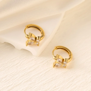Detail of 18K gold butterfly earrings with marquise-cut zircon stones on a white background