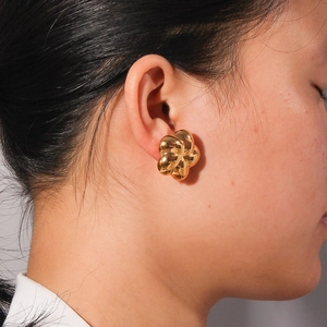Elegant 18K gold-plated hollow flower earrings with a polished mirror finish on model