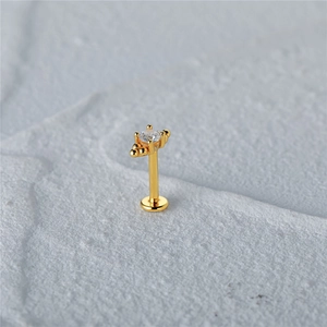 Macro shot of 16G gold butterfly flat back stud with shimmering zircon on textured stone