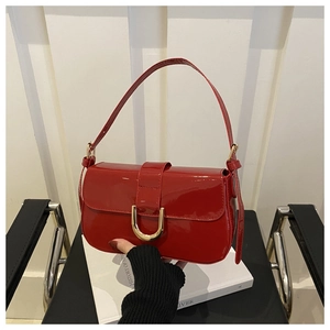 Detail shot of bright red patent leather handbag with gold horseshoe buckle on black chair