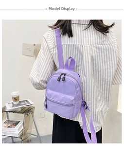 Rear view of a model wearing a mini purple nylon backpack with adjustable straps