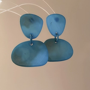 Detail of blue translucent acrylic earrings with irregular double layer pebble shapes