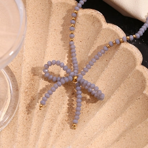 Détail macro des perles givrées lavande et accents dorés dans un design de nœud papillon