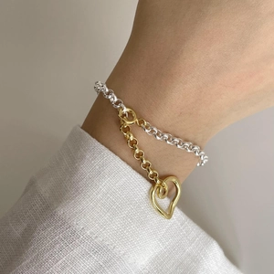 Two-tone S925 silver heart bracelet with gold and silver links on a model's wrist
