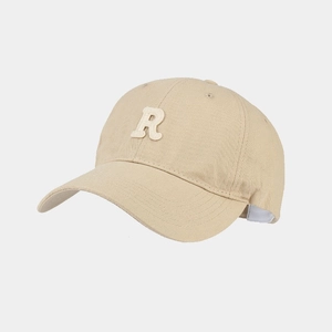 Dettaglio del tessuto in twill di cotone e lettera R ricamata bianca sul berretto beige