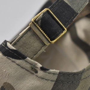 Detail of adjustable brass buckle and durable camo canvas fabric on the baseball cap
