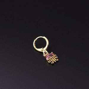 Detail of a golden jellyfish huggie earring with a pink zircon stone on a black surface