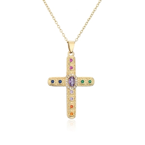 Macro detail of 18K gold plated cross pendant with colorful zircon stones and textures