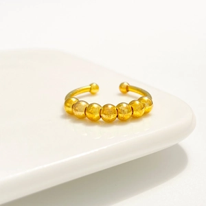 Makro-Detail eines goldenen Edelstahl-Angstringes mit sieben drehbaren Metallperlen
