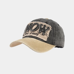 Detailansicht der Retro-Baseballkappe mit NOW-Aufnäher und modischen Fransenrändern