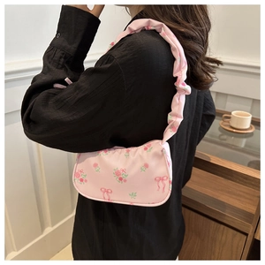 Detail view of pink rose pattern and ruffle cloud strap on a nylon underarm bag