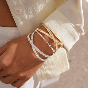 Close-up of luxury gold and silver layered beaded bracelets with pavé diamond accents