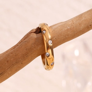 Makroaufnahme von 18K vergoldetem Ring mit Mikro-Pavé-Diamanten auf einem Holzstiel