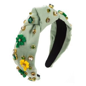 Detail of light green satin knotted headband with sewn crystal flowers and shamrocks