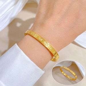 Close-up of gold titanium steel bangle showing detailed Roman numeral engravings