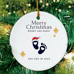 Ceramic Christmas ornament for parents-to-be hanging on a tree with festive lights