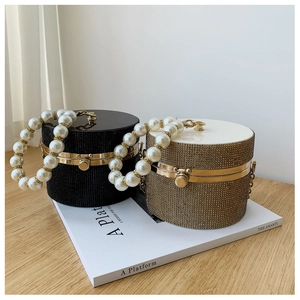 Detail of elegant cylindrical rhinestone clutch bags with large pearl handles and metal clasps
