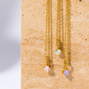 Detail of three gold titanium necklaces with round pink, white, and purple gemstones