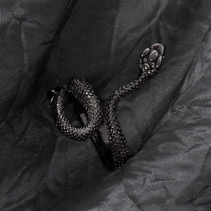 Detail of snake ring with black plating and textured scales on dark fabric