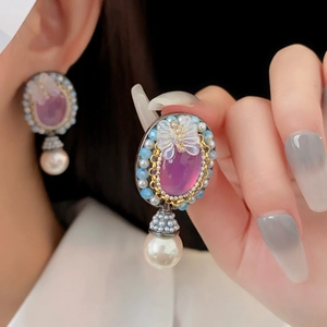 Dettaglio di orecchini vintage con pietra preziosa viola e accenti di perle