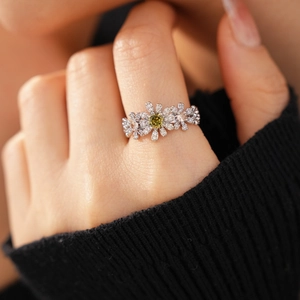 Close-up of a zircon flower ring featuring a yellow center stone on a hand with black sleeve