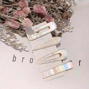 Iridescent four-piece hair clip set with pearl shell finish on white display card
