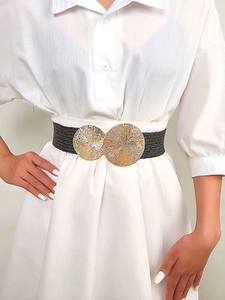 Women's black woven elastic waist belt with large dual gold metal buckles on a dress