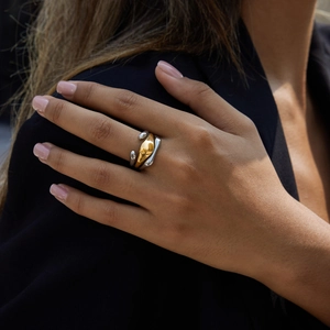 Detailed close-up of a two-tone 18K gold and silver layered ring on a finger