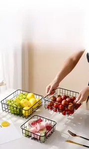 Close-up of black metal wire fruit baskets in three sizes on a marble table surface