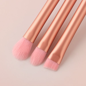 Detailed view of rose gold makeup brushes with soft pink bristles on a soft pink background