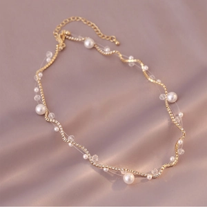 Elegant gold wavy chain necklace with white pearls on soft silk background
