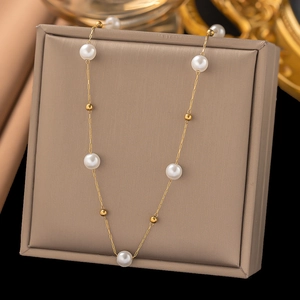 Elegant gold chain necklace with round white pearls and gold beads on a jewelry display