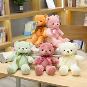 Juego de coloridos ositos de peluche con cintas de raso en un cálido escritorio de madera.