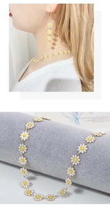 Detailed close-up of white daisy pendant necklace and hanging floral earrings set