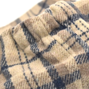 Macro shot of thick plaid wool fabric texture and elastic waistband detail on newsboy cap
