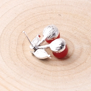 Macro view of stylish 3D cherry earrings with red beads and silver metal leaves