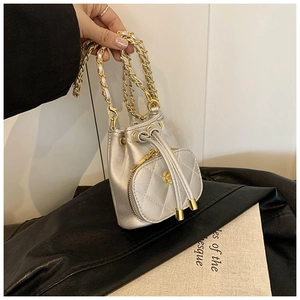 Close-up of a silver quilted mini bucket bag with chain strap and drawstring closure