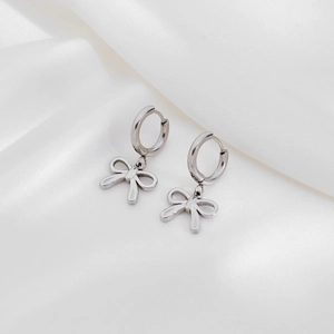 Polished stainless steel hoop earrings with hanging bow pendants on white silk fabric